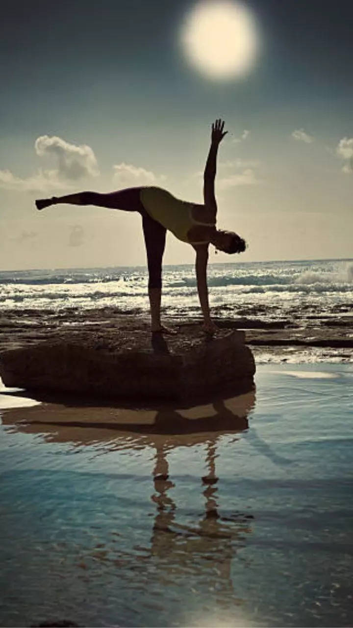 A woman doing a yoga pose on a beach photo – Yoga pants Image on Unsplash