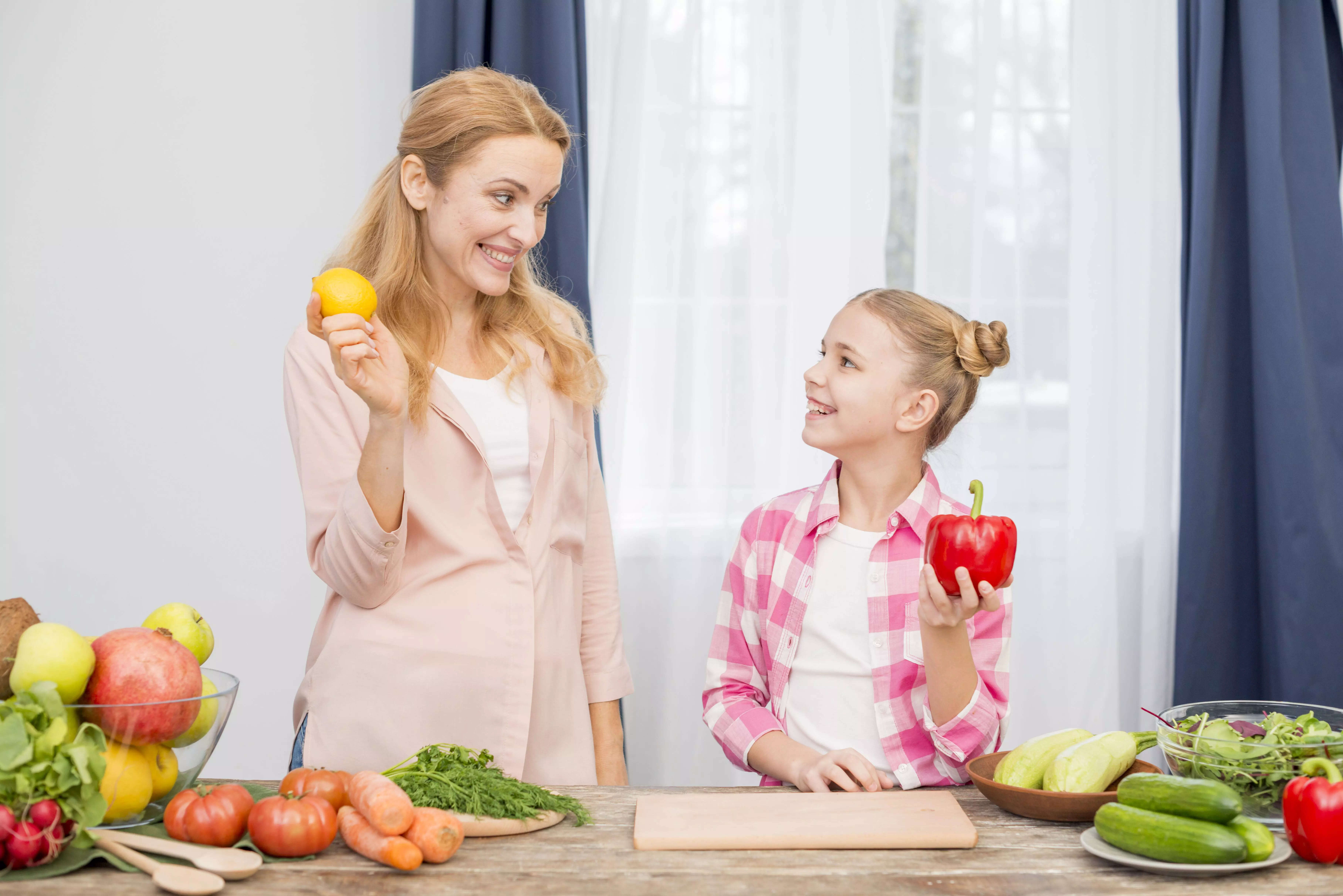 smiling-mother-daughter-holding-yellow-lemon-red-bell-pepper-hand 1