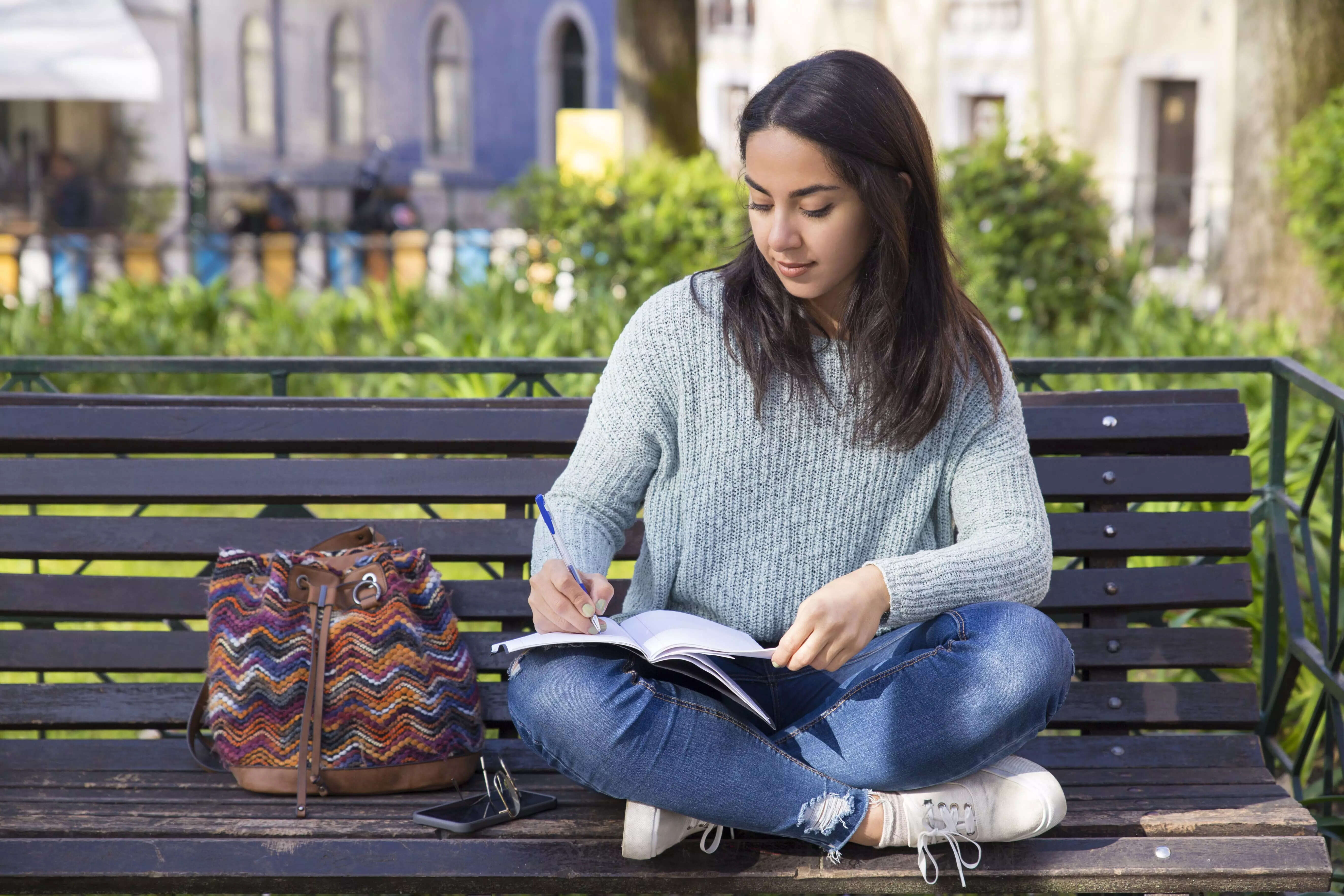 serious-woman-making-notes-sitting-bench-outdoors 1
