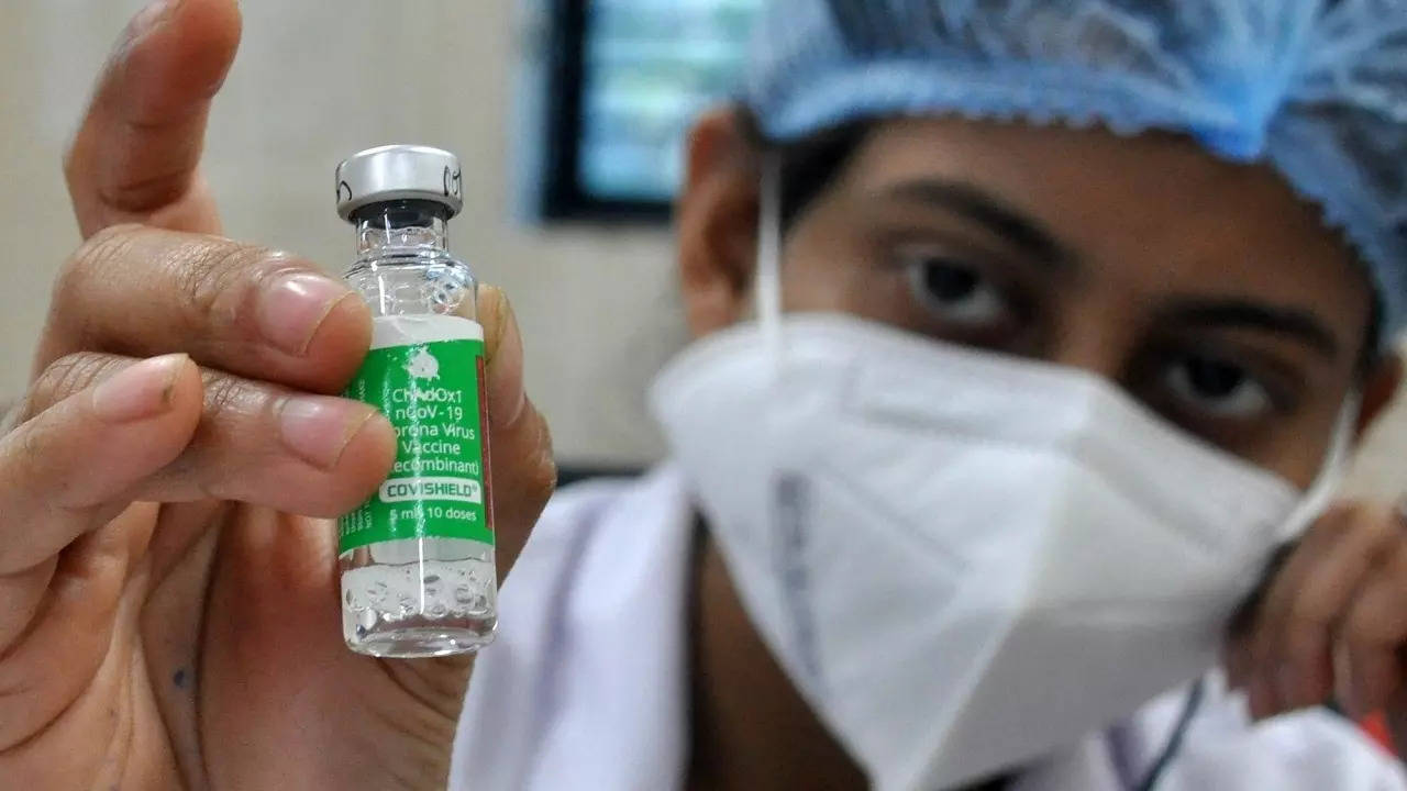 ​A health worker shows a vial of Covishield vaccine before administering the same to an elderly man at a government hospital in Kolkata​