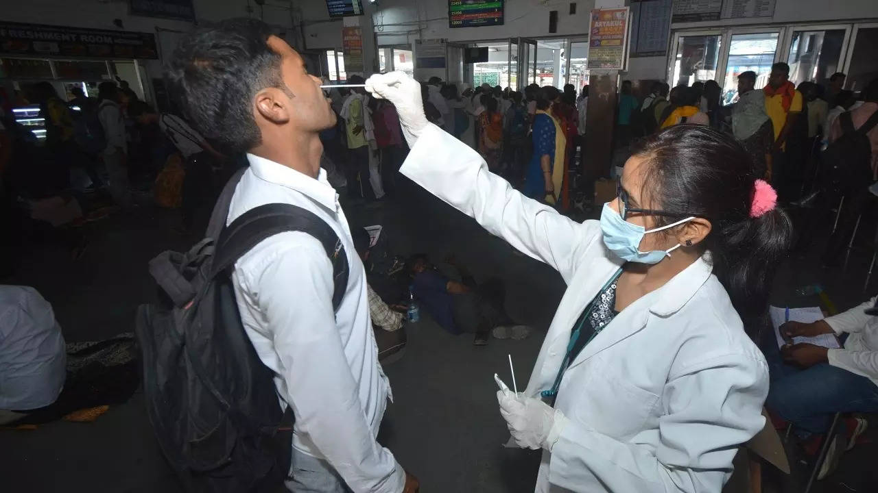A health worker collects swab sample from passengers for COVID-19 test, at Charbagh railway station in Lucknow
