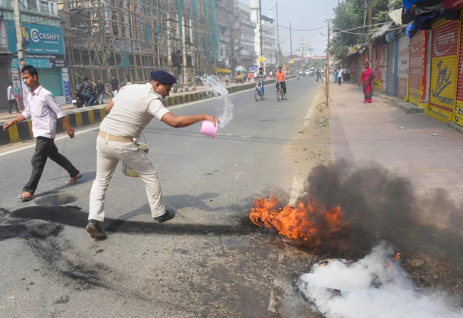 Patna: Police try to douse burning tyres during the Bihar Bandh during the Bihar...