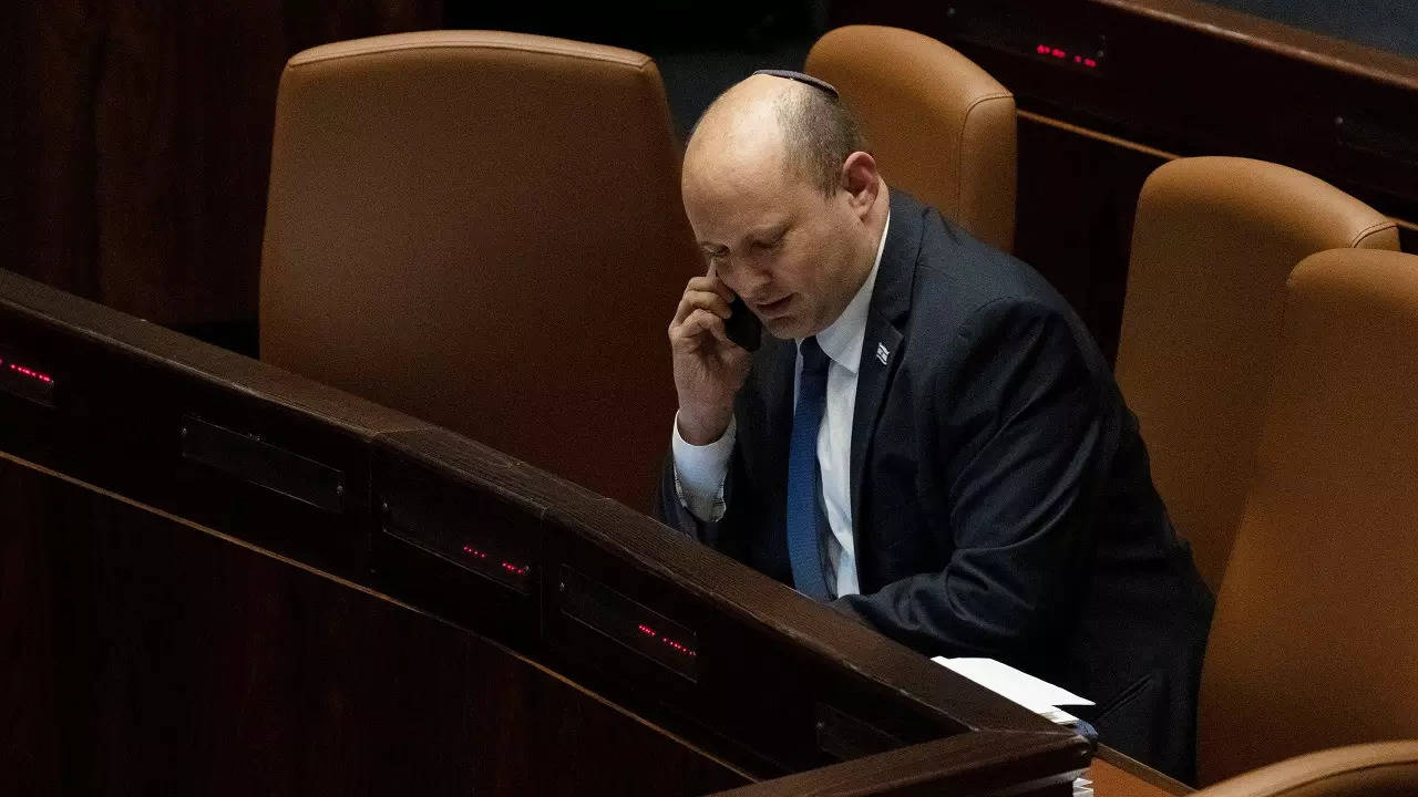 Israeli Prime Minister Naftali Bennett makes a call before voting on a law on the legal status of Jewish settlers in the occupied West Bank, during a session of the Knesset