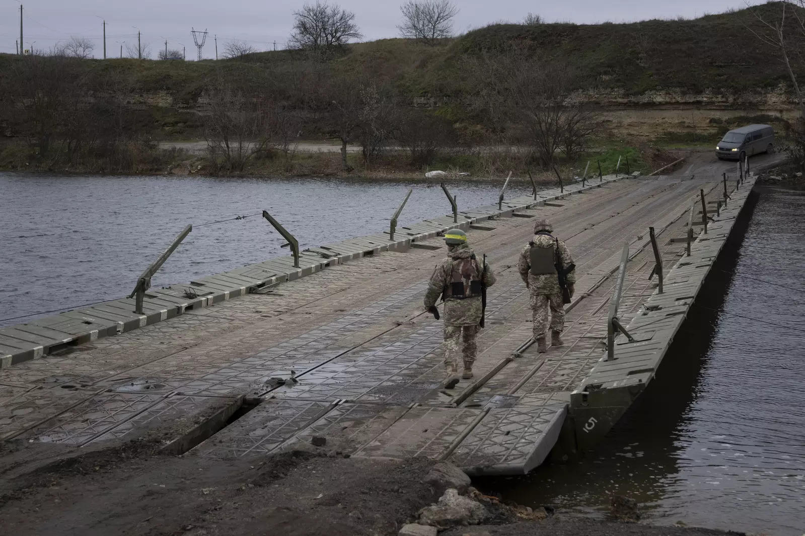 Ukrainian servicemen walk on a pontoon bridge across the Inhulets river in Kherson region