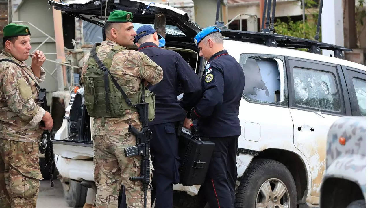 UN peacekeepers military police, right, investigate a damaged vehicle at the crime scene