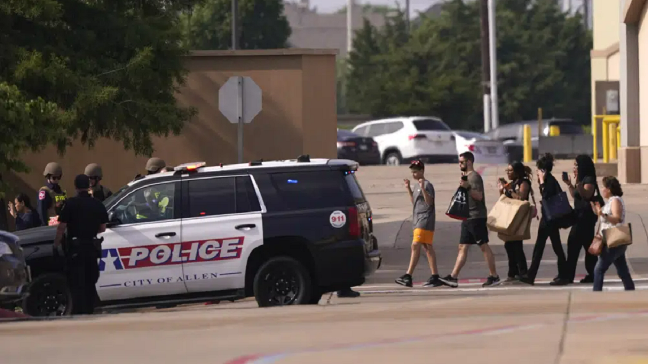 People raise their hands as they leave a shopping center following reports of a shooting, Saturday, May 6, 2023, in Allen, Texas.