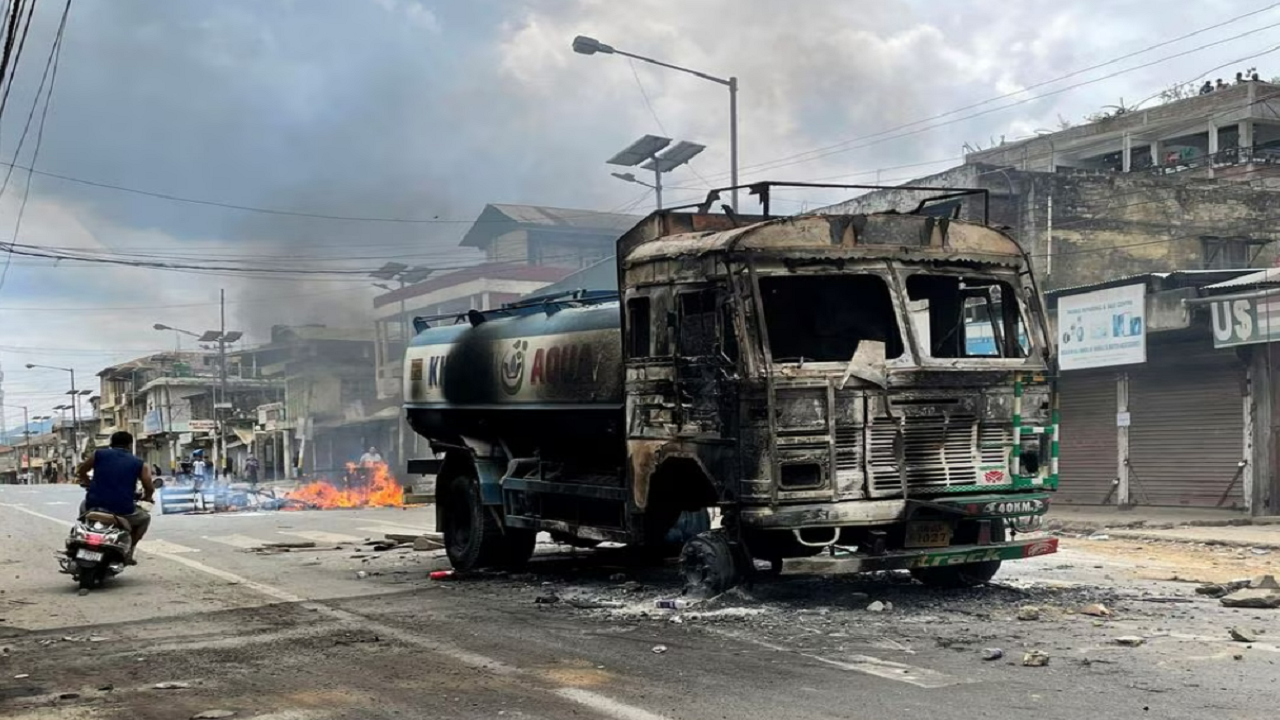 A scooterist rides past a damaged water tanker that was set afire during a protest by tribal groups in Churachandpur in the northeastern state of Manipur, India, May 4