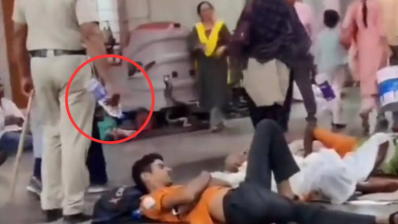 A police officer sprays water on passengers sleeping on Pune Railway Station's platform | Screenshot from Twitter video