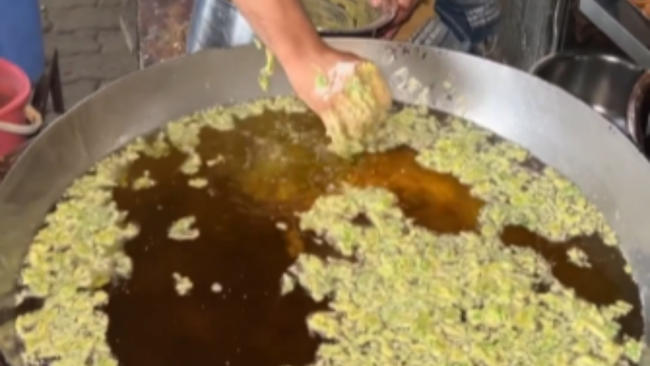 Pakoda seller dips his hand in hot oil.