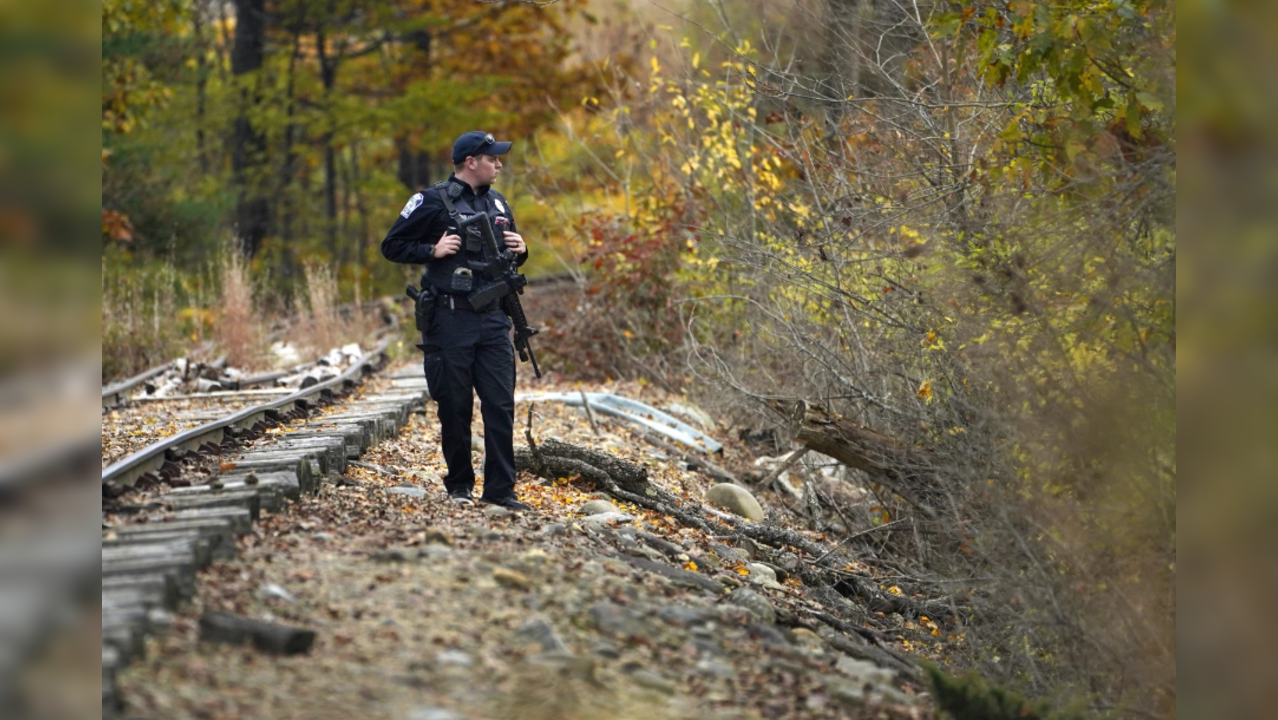 A police officer searches along railroad tracks after deadly mass shootings