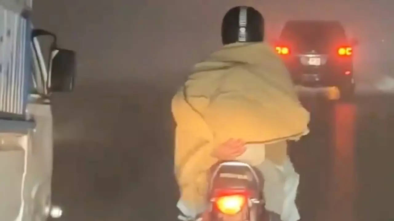 A father holds his pillion-riding son with one hand on a motorcycle. | Screengrab from viral video