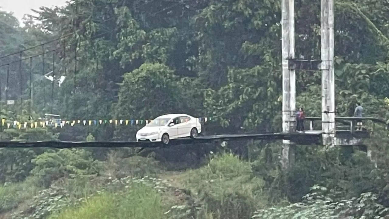 Pedestrians look on as a Thai woman's car is perched precariously on narrow bridge in Phrae. | Credit: WeirdKaya