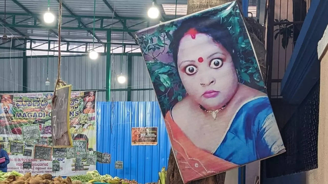 A photo of a woman believed to ward off evil eye guards a Bengaluru vendor's tomatoes. | Niharika Rao