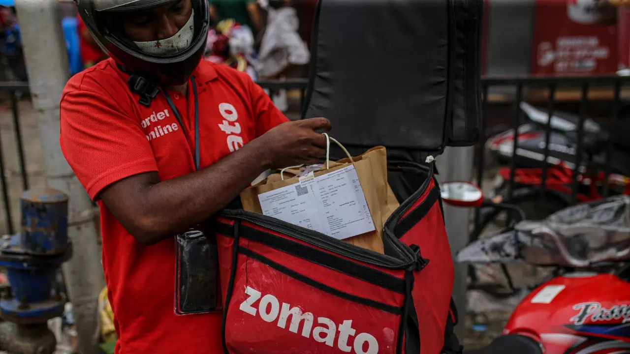 A Zomato delivery driver places a food order into their bag for drop-off. | Dhiraj Singh/Bloomberg