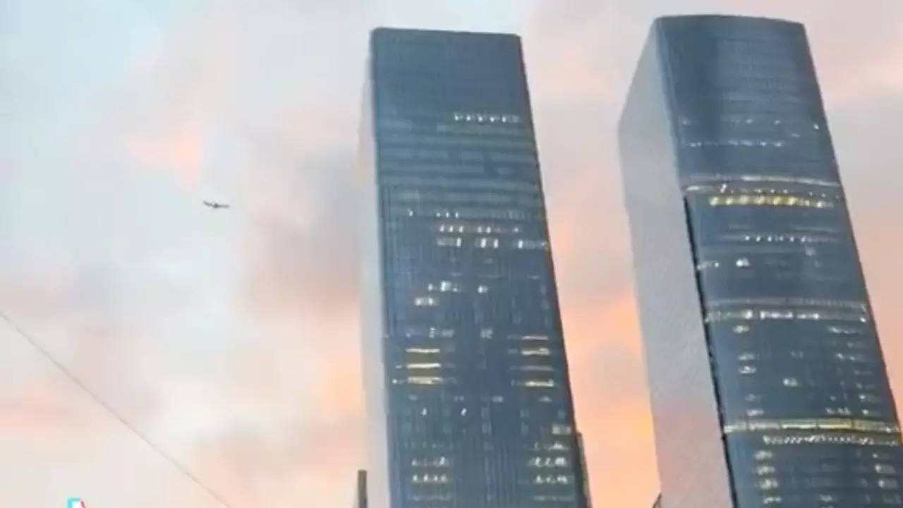 A plane flies behind twin New York City buildings One and Two Manhattan West. | @genderenvier/X