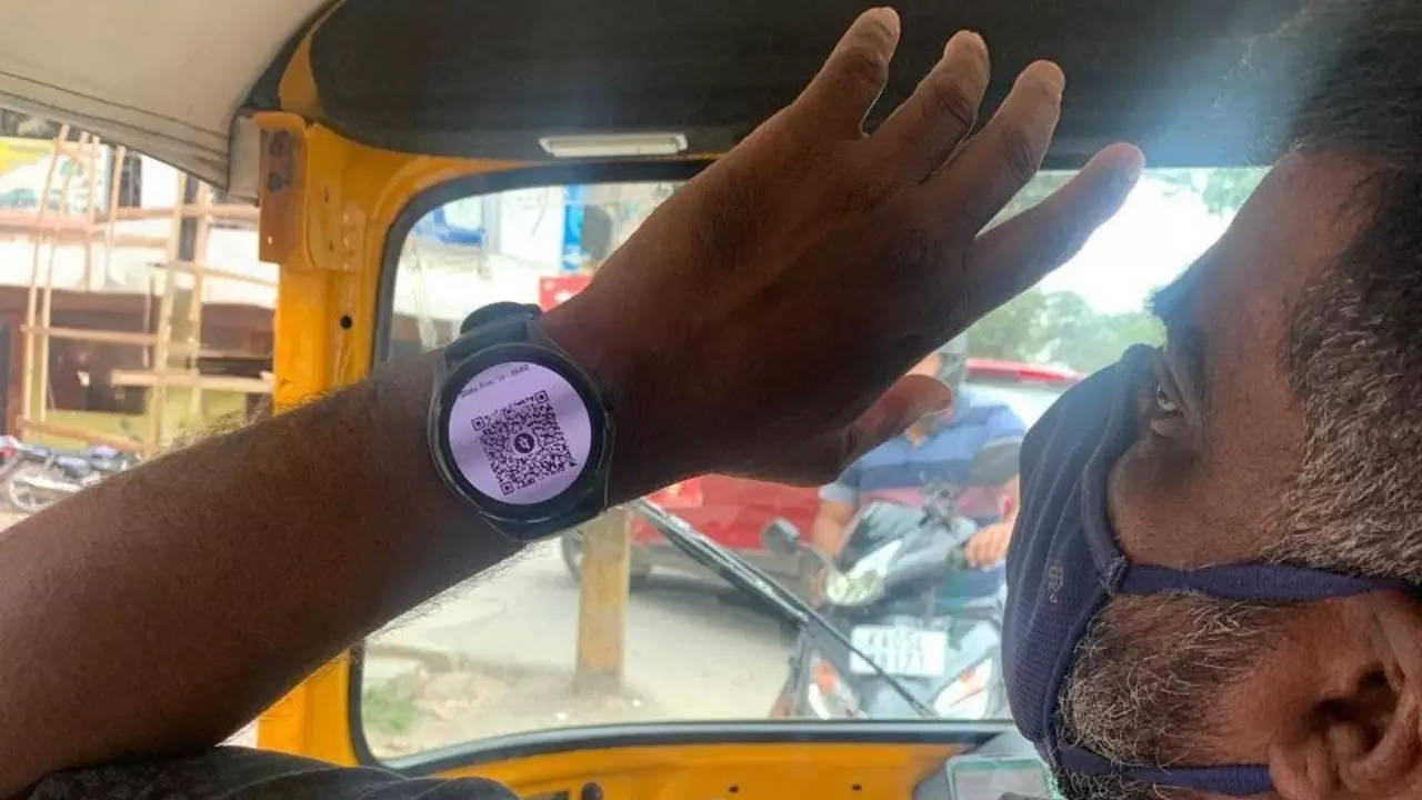 An auto driver shows his rider a payment QR code on his smartwatch in Bengaluru. | Courtesy: Vishvajeet/X