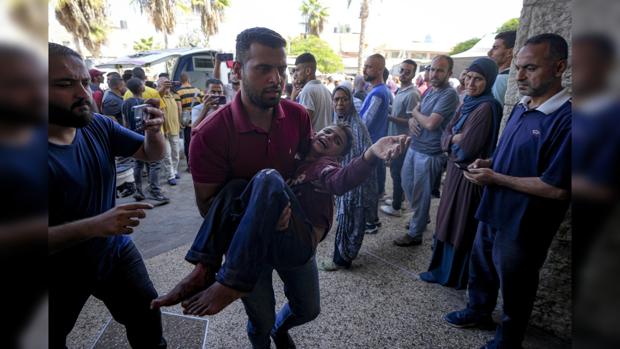 A man carries an injured child to hospital following Israeli airstrike on Gaza school