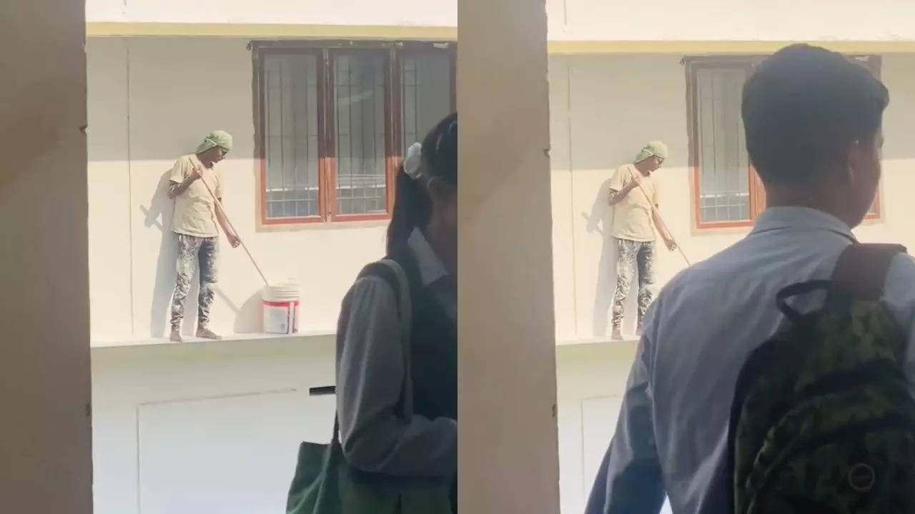 A painter pauses work for the national anthem, while school students walk in front of the camera