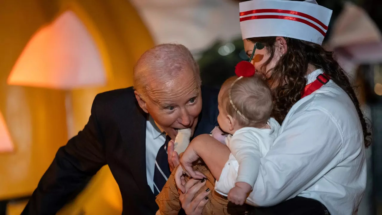 Joe Biden bites a baby's foot during the White House Halloween party. | Image courtesy: AP