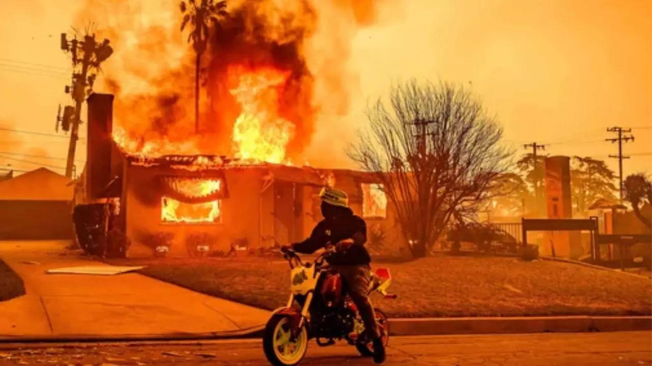 A motorcyclist stops to look at a burning home during the Eaton fire in the Altadena area of Los Angeles county.(AFP)