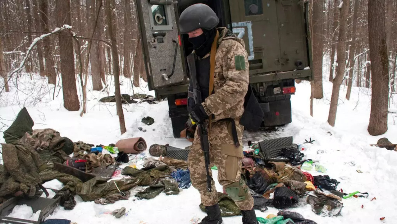 A volunteer of the Ukrainian Territorial Defense Forces inspects a damaged military vehicle in the outskirts Kharkiv