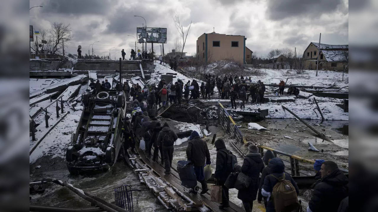 Ukrainians cross an improvised path under a destroyed bridge while fleeing Irpin, in the outskirts of Kyiv