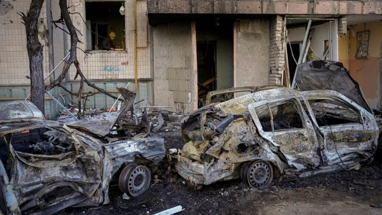 A woman cleans up her kitchen from debris in an apartment block damaged by a bombing the previous day in Kyiv