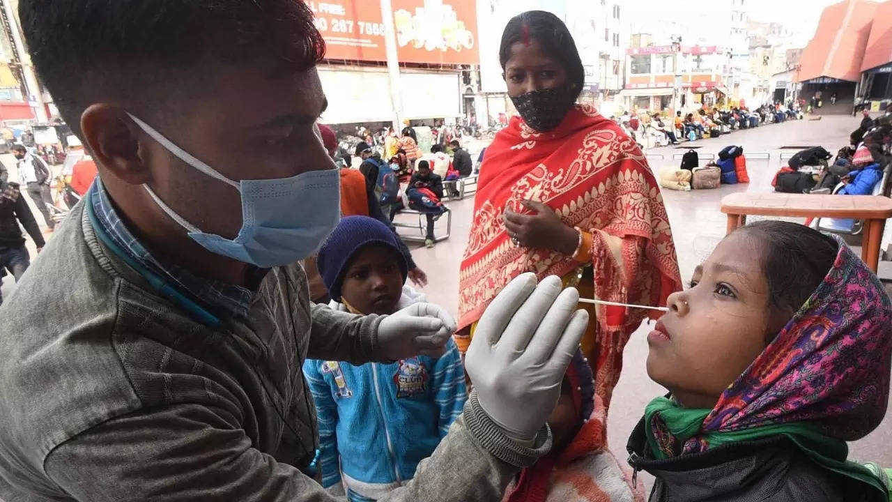 ​A healthcare worker collects swab samples from passengers for COVID-19 test at Patna Railway station