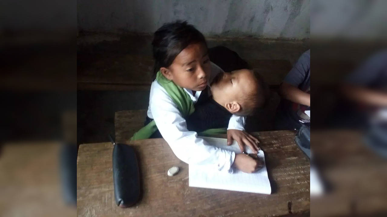 Manipuri girl attends class with sister in her lap