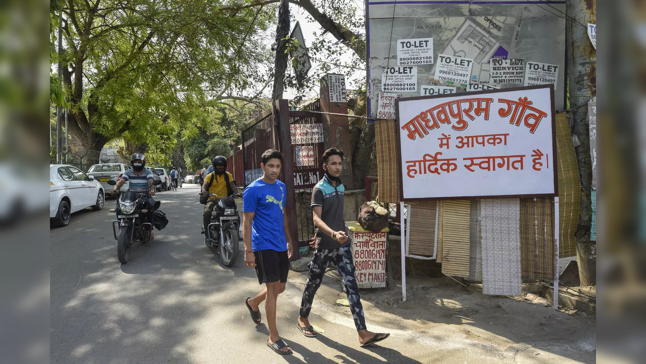 New Delhi: Locals near a board with the message ‘Welcome to Madhavpuram’ at the ...