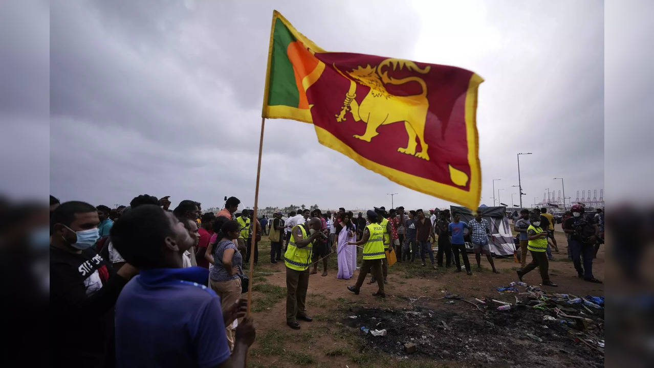 A Sri Lankan man holds a national flag as police officers conduct investigations into aftermath of clashes between government supporters and anti government protesters in Colombo.