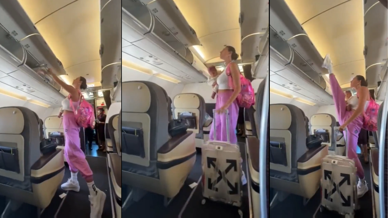 Woman with baby in hand closes overhead cabin on plane with her foot