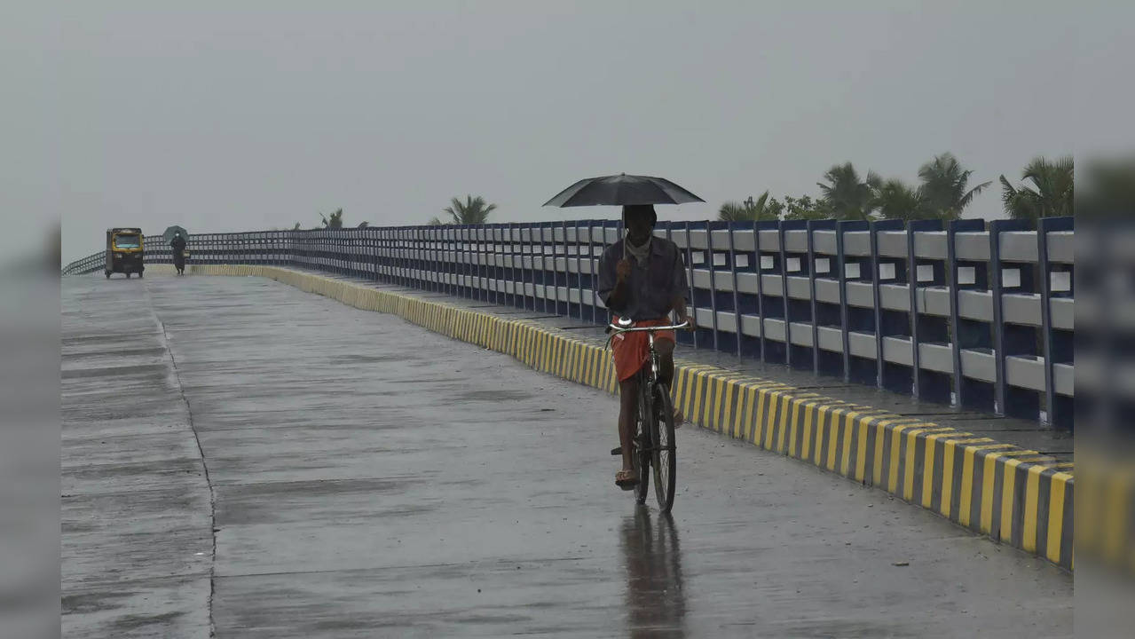 **EDS: RPT, ADDS DETAILS** Kochi: A commuter holds an umbrella as he rides a bic...