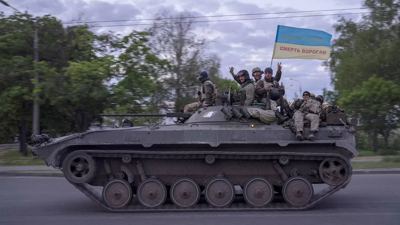 Ukrainian serviceman wave a flag with writing in Ukrainian as they ride atop a tank in the Kharkiv region