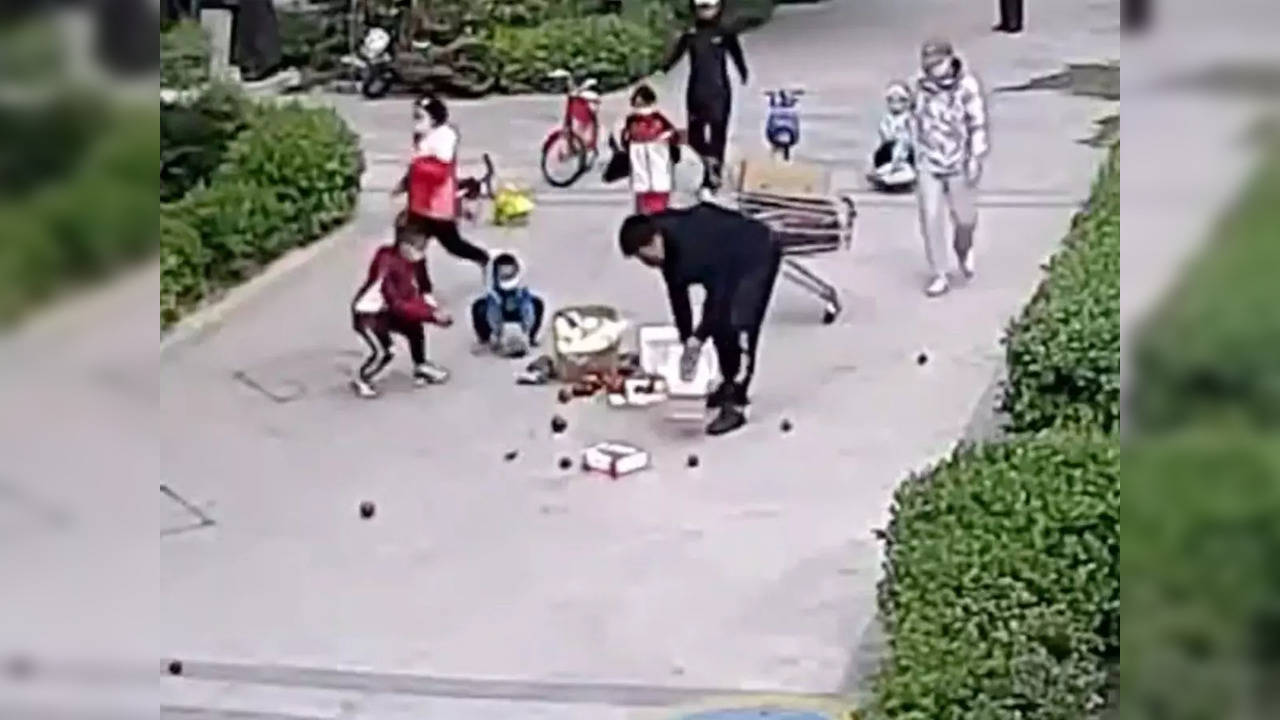 Children pick up fruits after a man's shopping flips and spills the fruits everywhere | Image credit: Twitter