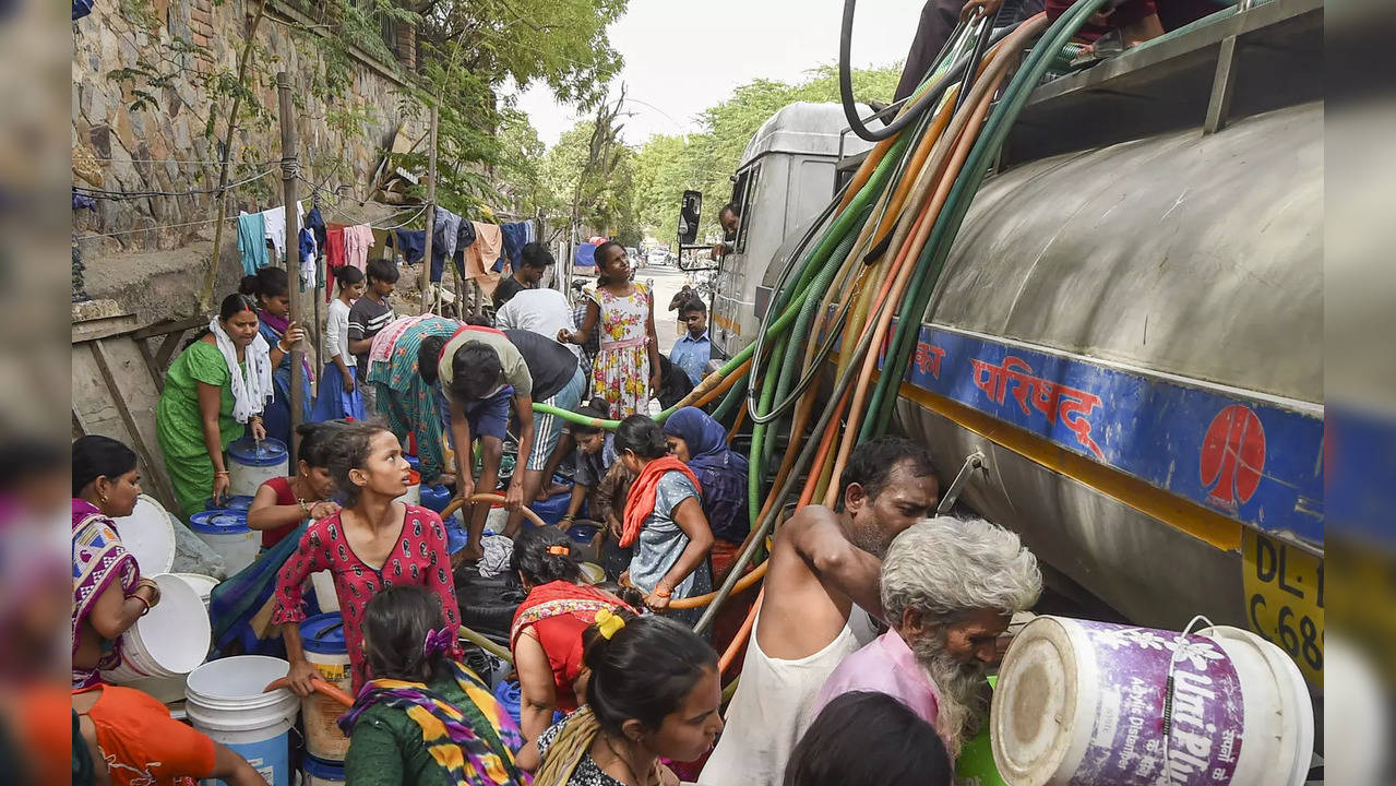 New Delhi: Locals collect drinking water from a tanker, amid a water crisis amid...