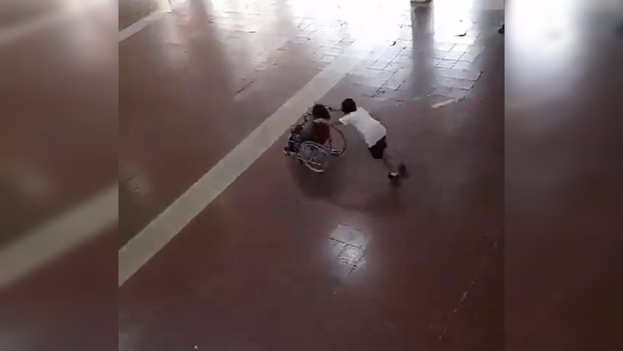 Boy pushes wheelchair of his friend sports day