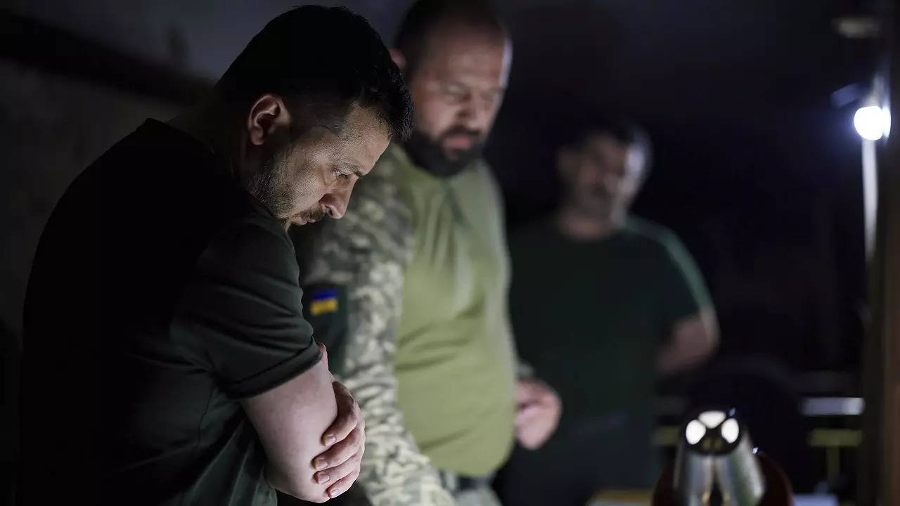 Ukrainian President Volodymyr Zelenskyy, left, listens to a servicemen report close to front line in Donetsk region