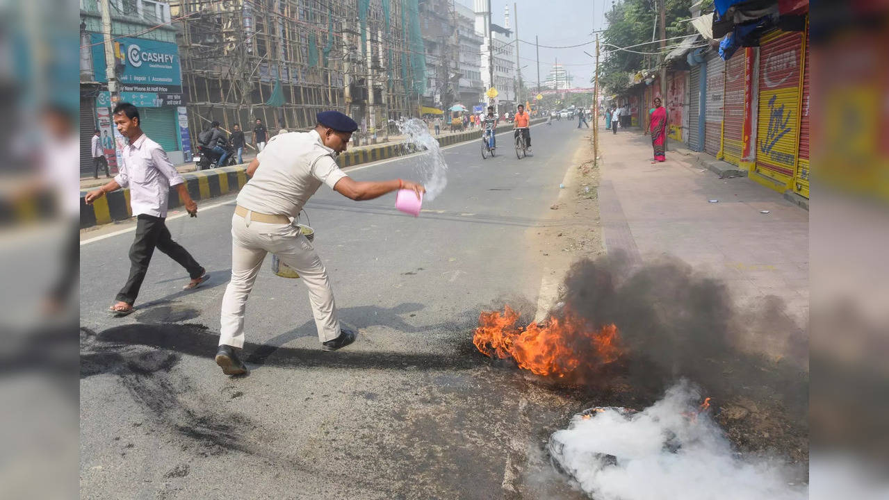 Patna: Police try to douse burning tyres during the Bihar Bandh during the Bihar...