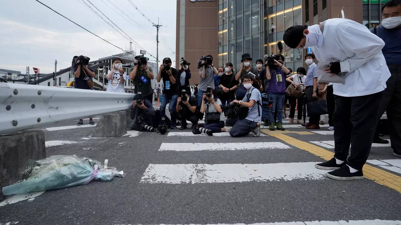 A man prays after putting a bouquet of flowers at a makeshift memorial at the scene where the former Prime Minister Shinzo Abe was shot while delivering his speech