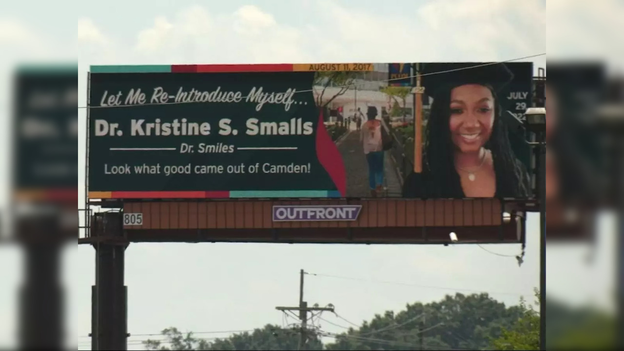 A hoarding congratulating Dr. Kristine S. Smalls on receiving her doctorate sits over a busy street in Camden, New Jersey