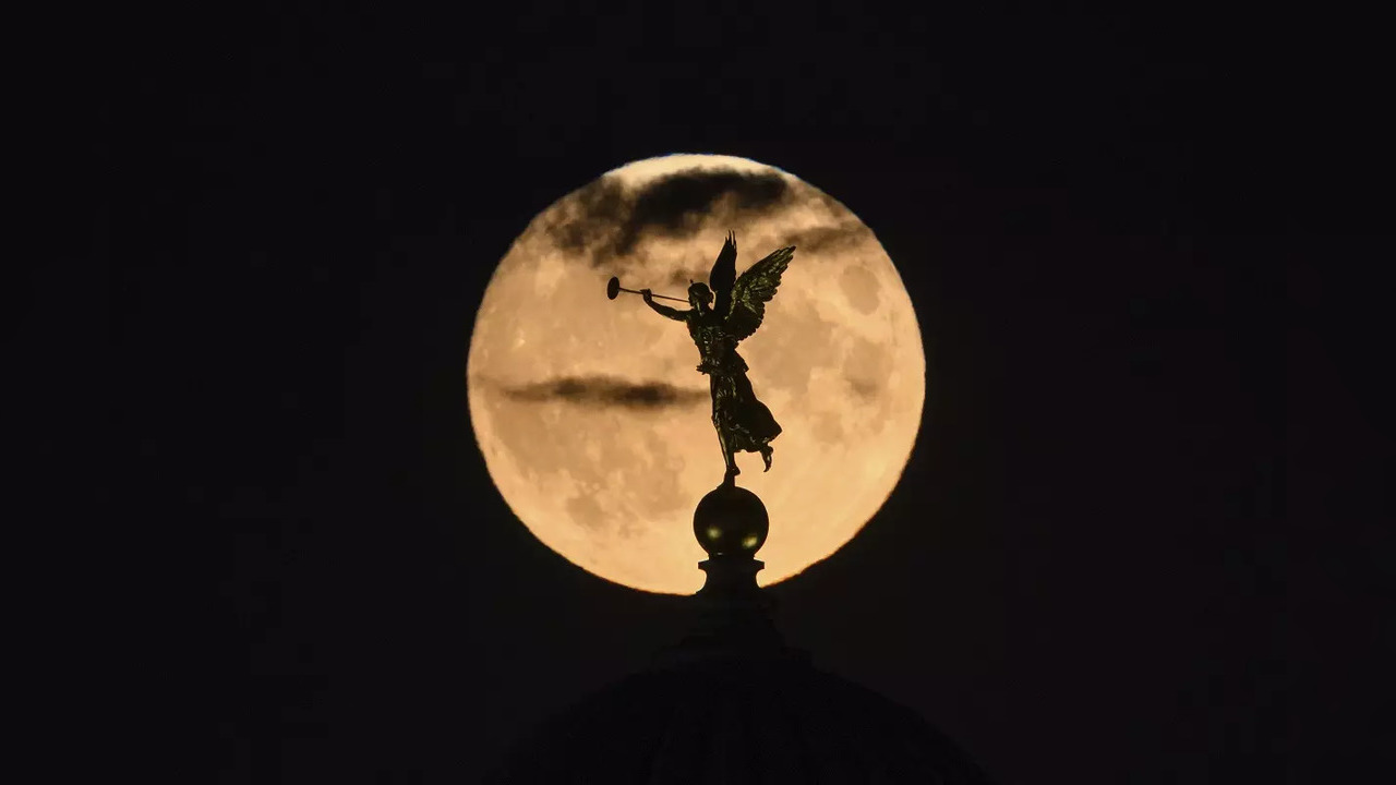 The supermoon rises in the evening behind the dome of the Academy of Fine Arts with the angel Fama in Dresden, Germany.