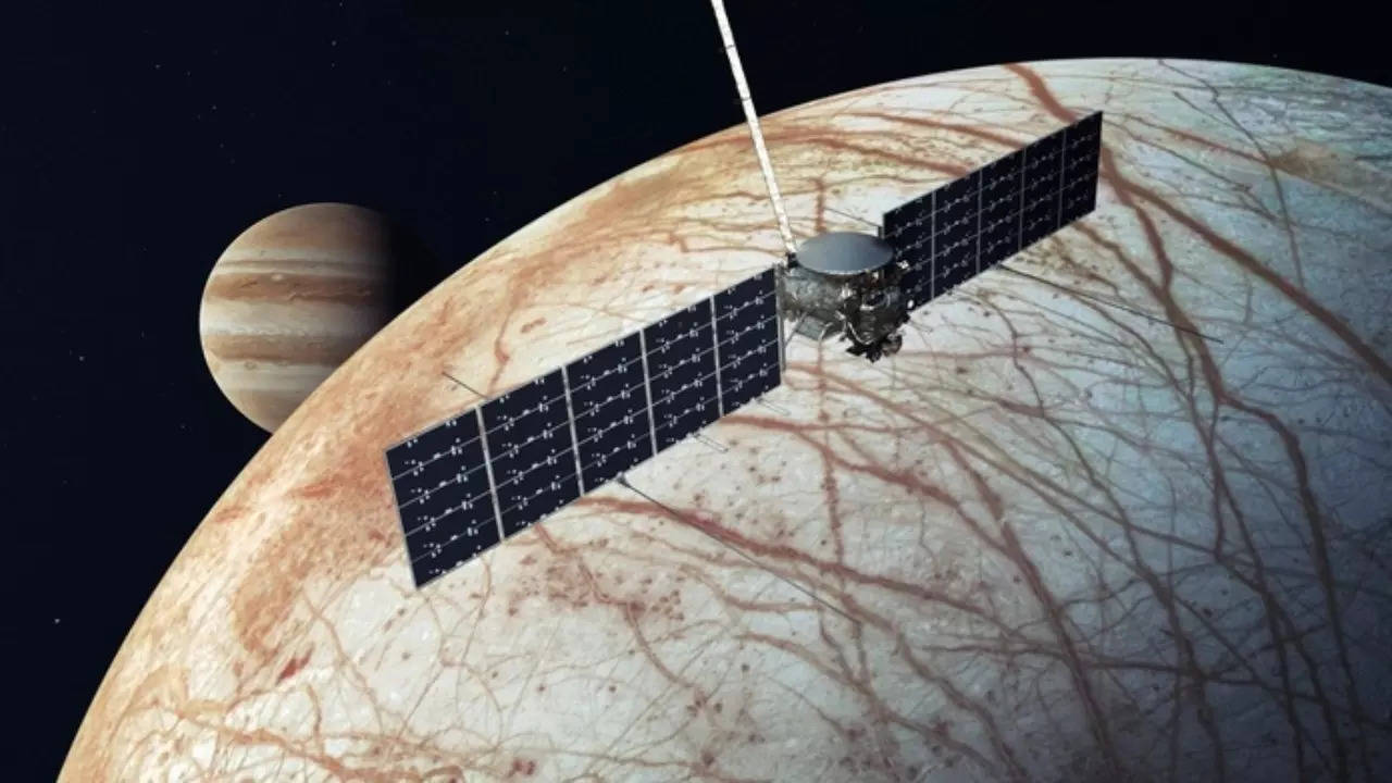An illustration of NASA's Europa Clipper spacecraft flying by Jupiter's moon Europa