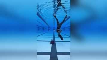 Un nadador profesional camina boca abajo dentro de la piscina con tacones altos y gira 360 grados