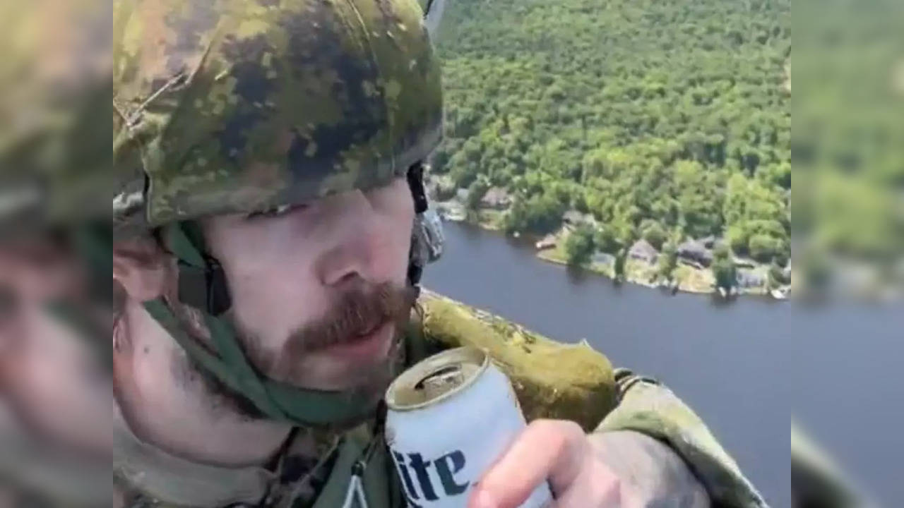 A Canadian soldier drinks beer during parachute training