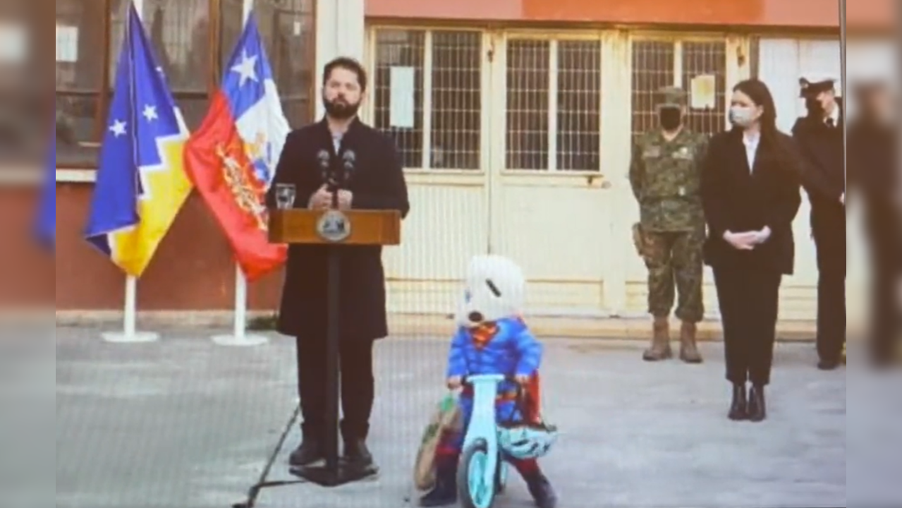 Child cycles around Chile President in Superman costume