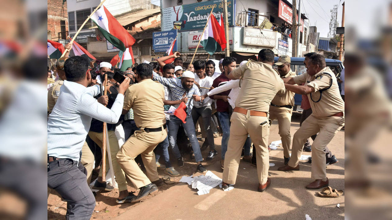 Police attempt to detain Popular Front of India and Social Democratic Party of India workers during a protest against the NIA raid