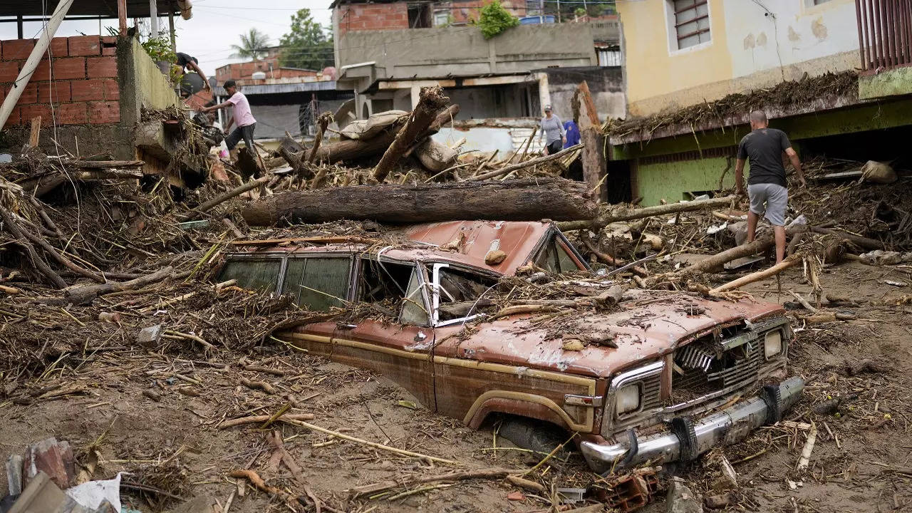 Residents walk through the debris left by flooding caused by a river that overflowed after days of intense rain in Las Tejerias