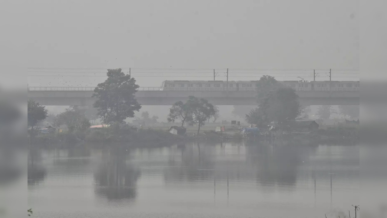 New Delhi, Oct 12 (ANI): A metro train running near NH-24 on a foggy morning, in...