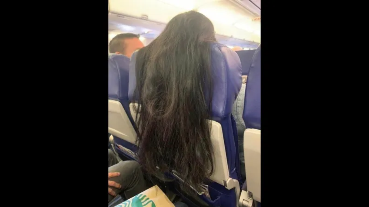 Woman's hair dangle over passenger's tray table on flight